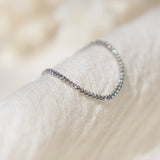 Delicate solid platinum chain ring for women on a textured beige surface