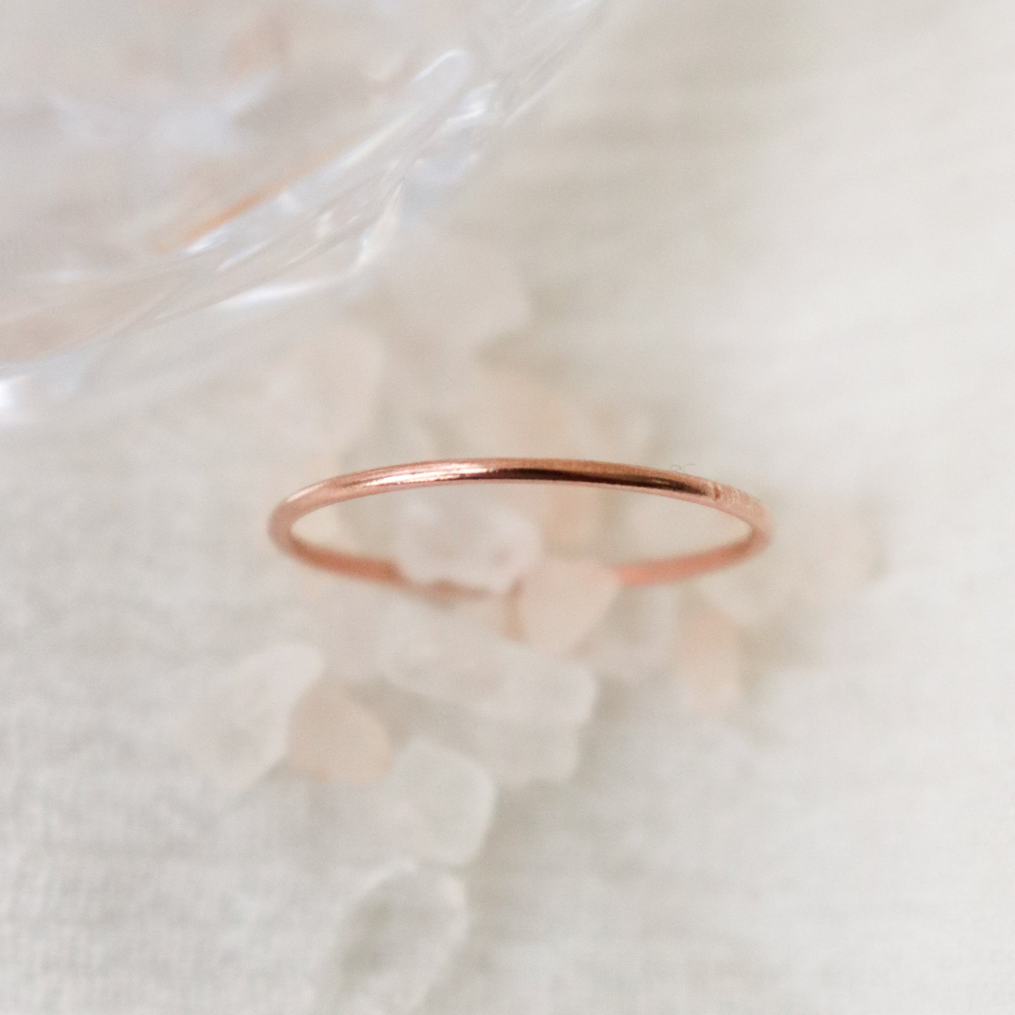 Rose gold women's finger ring on a soft white blurred crystal and fabric background