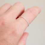 Silver ring on a woman's finger against a neutral background