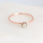 Minimalist cremation ring featuring a small, round, cabochon setting in rose gold fill on a light background.