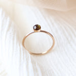 Small gold memorial ring with a dark chocolate colored resin ashes cabochon with gold flecks on a light background. By Meadowbelle Jewelry.