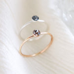 Two hand made, minimalist memorial rings on a light background. One ring is silver and the other ring is gold fill. Small, round resin cabochons hold ashes inclusions with custom color added.