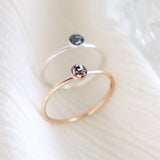Two hand made, minimalist memorial rings on a light background. One ring is silver and the other ring is gold fill. Small, round resin cabochons hold ashes inclusions with custom color added.