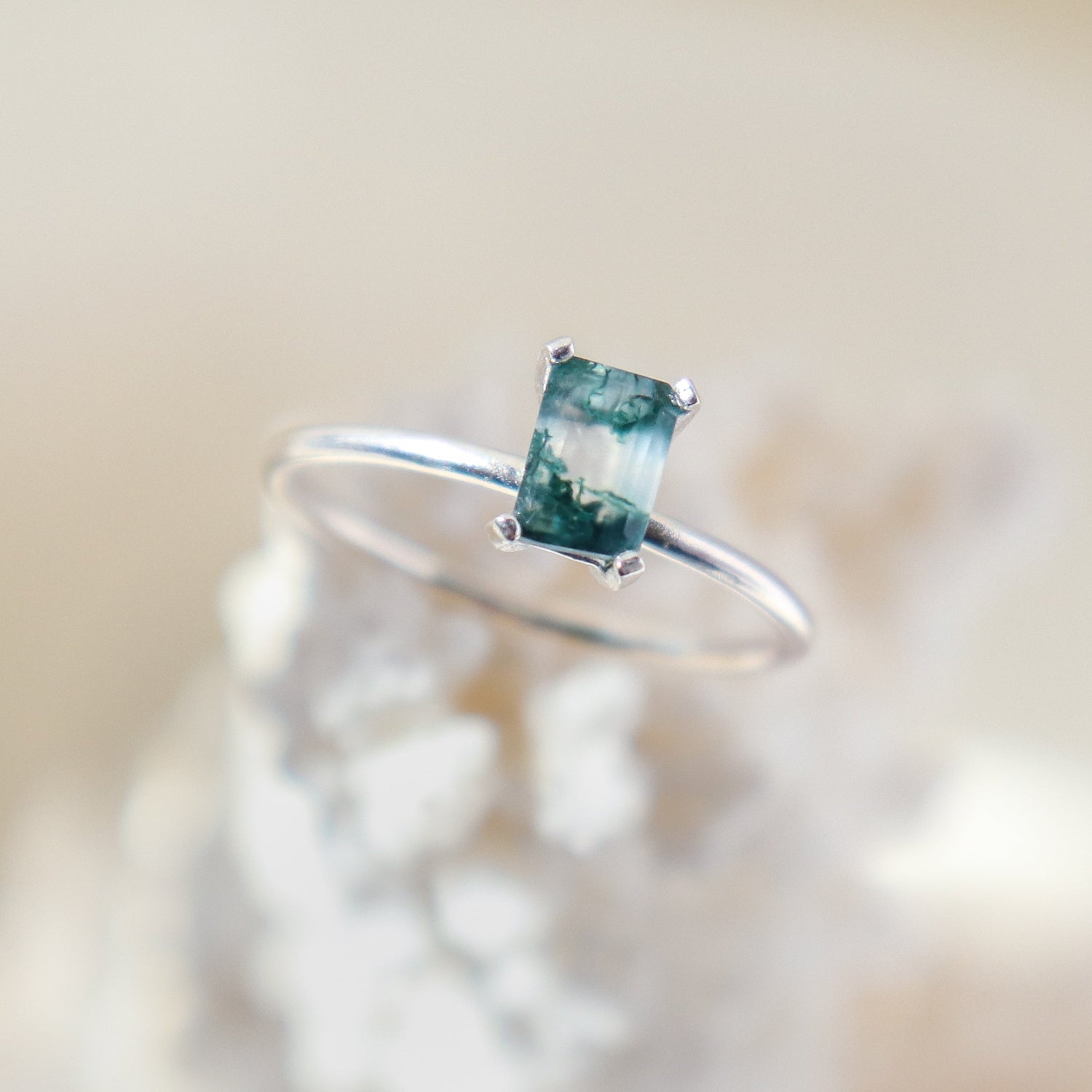 Rectangle shaped natural moss agate gemstone ring in a solid sterling silver setting with a smooth, round band. The stone shows lots of natural veining with pockets of clear in the stone as well.