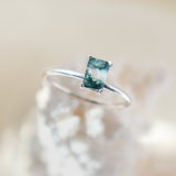 Rectangle shaped natural moss agate gemstone ring in a solid sterling silver setting with a smooth, round band. The stone shows lots of natural veining with pockets of clear in the stone as well.