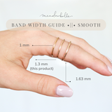 A hand wearing three slim smooth metal bands with overlaid width measurements labeled 1 mm, 1.3 mm (this product), and 1.